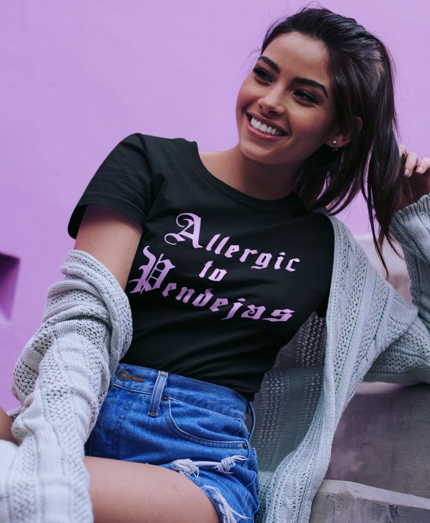 Latina woman in funny black t-shirt with pink old english lettering that says ALLERGIC TO PENDEJAS
