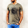man wearing a Masculine 'My Birthplace My Blood' olive green T-Shirt with bold American flag and crested caracara design in a gear-shaped circle