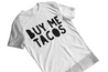 A  mens funny white t-shirt with bold hand-drawn lettering that reads 'buy me tacos'