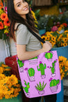 Hispanic woman carrying a Latina-inspired large tote bag to celebrate Latino culture.  The background is pink and the graphic is cactus themed with a variety of cartoon cacti., with the phrase "know your roots"