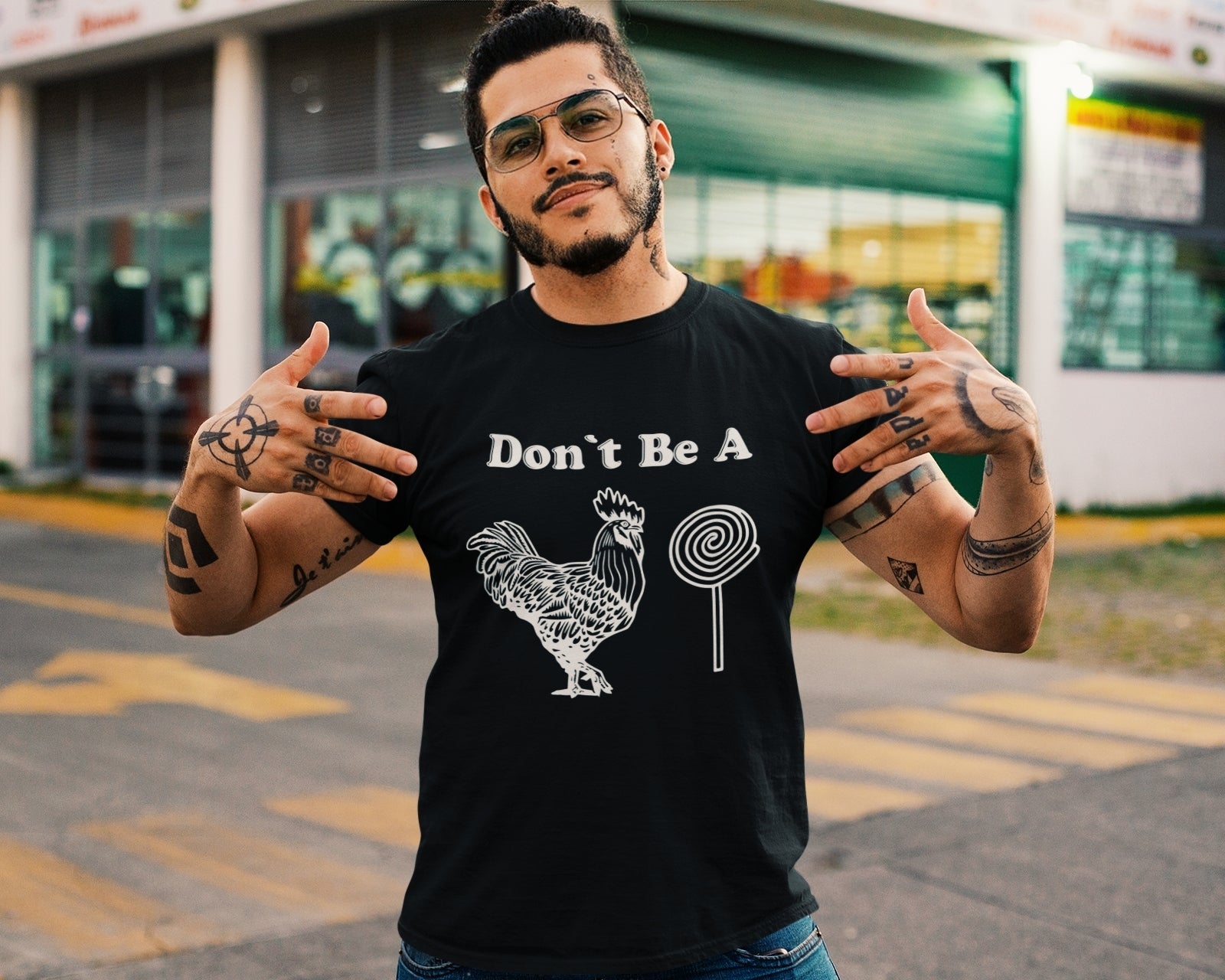 Mexican man wearing a black t-shirt with a lighthearted play on words graphic featuring a rooster and a lollipop