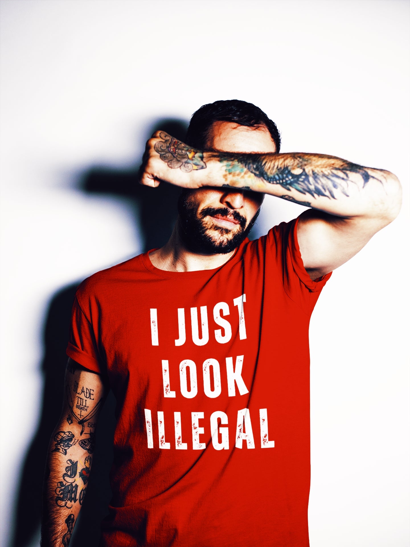 mexican man wearing a Funny and bold t-shirt for  Hispanic men, with the graphic 'I Just Look Illegal' in a streetwear font on a red shirt