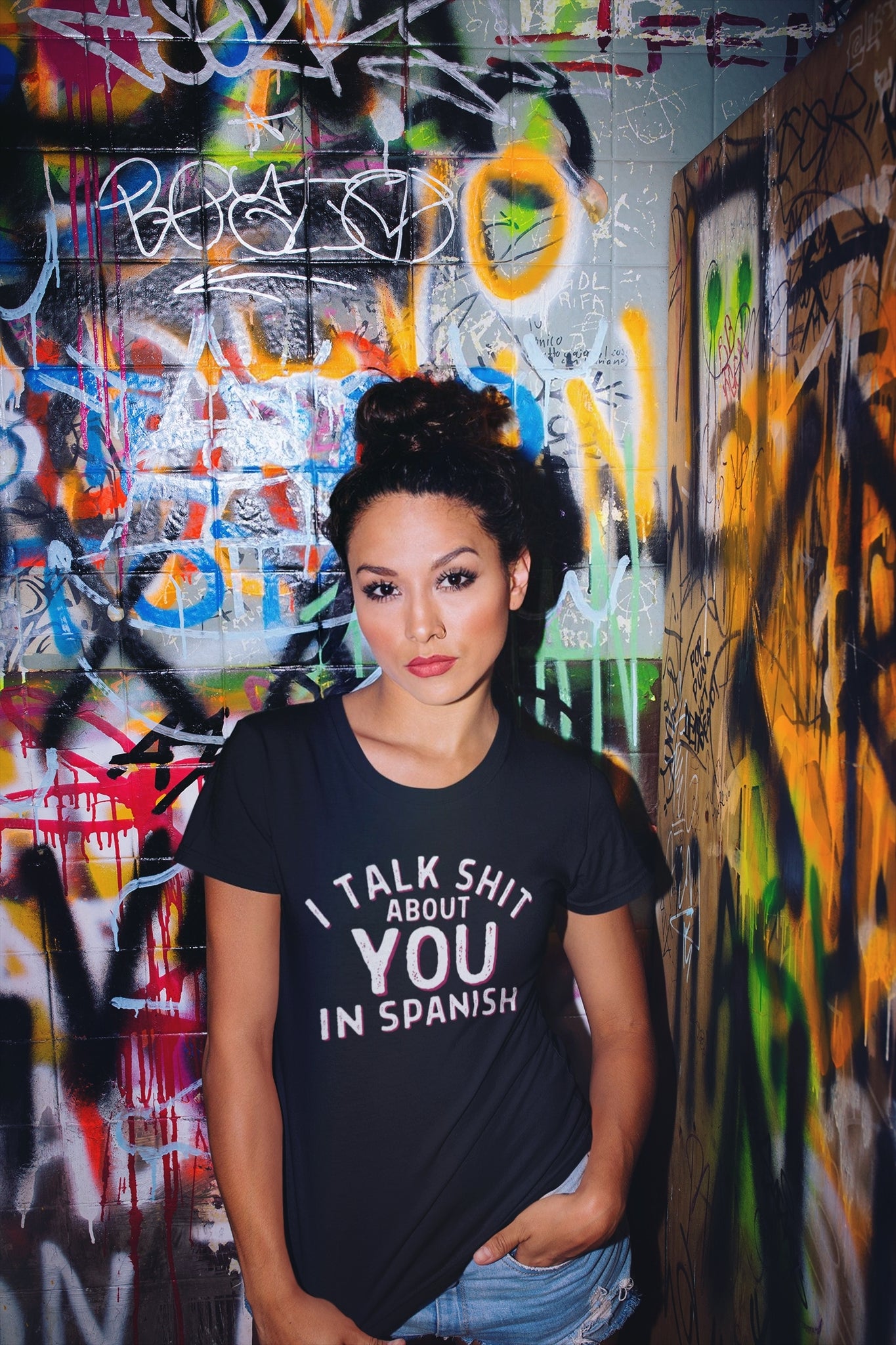 Latina woman wearing a Humorous black  t-shirt  with 'I talk shit about you in Spanish' text design