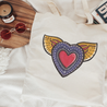 The graphic on this canvas tote bag features a colorful, graffiti-style heart with golden wings, representing freedom