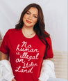 woman wearing Powerful 'No human is illegal on stolen land' T-Shirt with eye-catching pink handwritten text on a red background