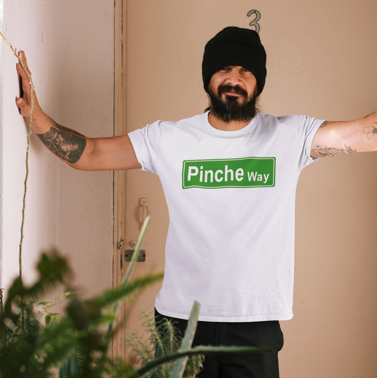 mexican man wearing a T-shirt showcasing a funny green street sign graphic with the words 'Pinche Way'