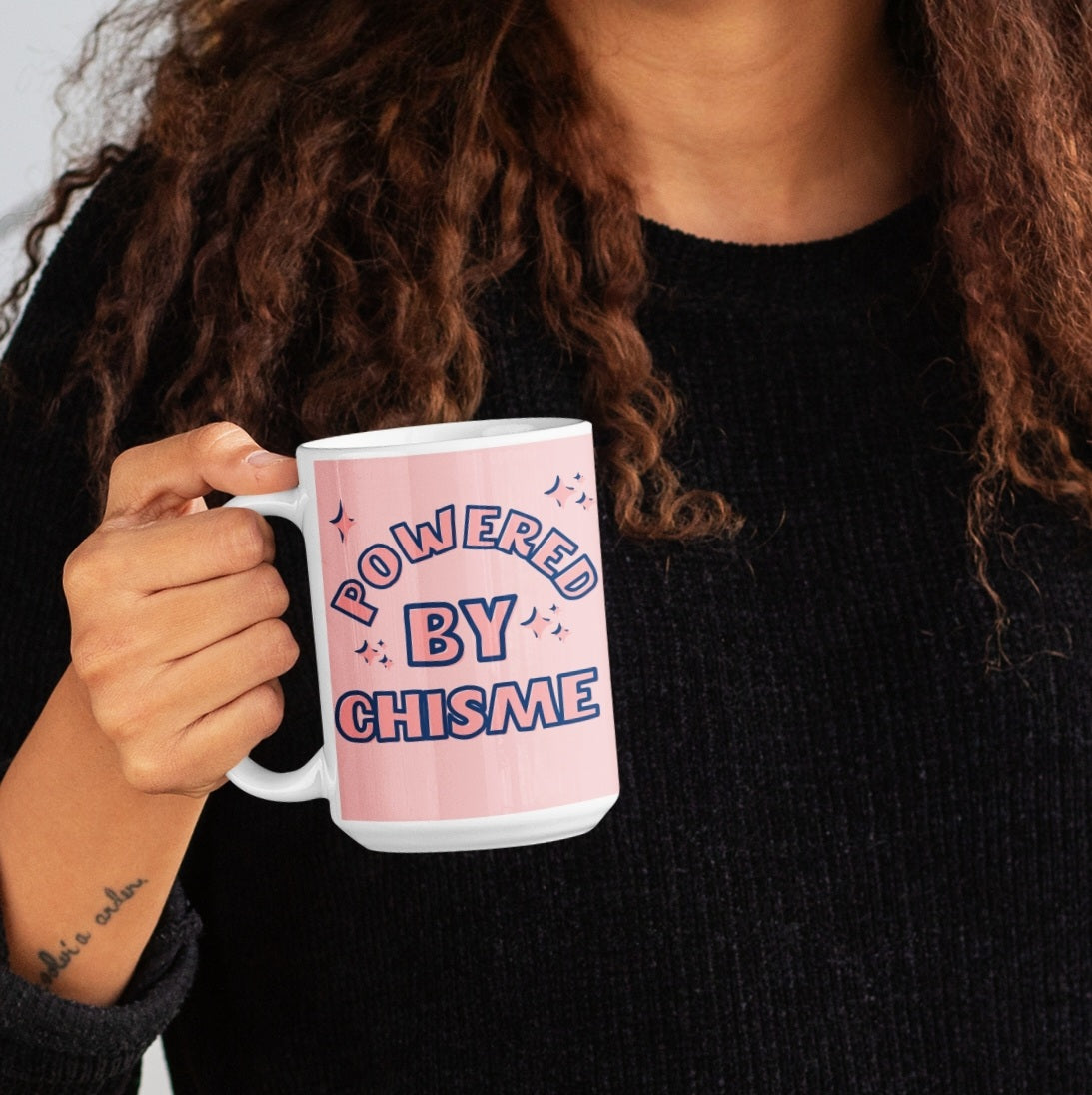 Hispanic woman holding a funny tall white mug for Latinas and Spanish-speakers. In pink and blue lettering, the graphic states "powered by chisme"