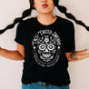 woman wearing black t-shirt with white dia de los Muertos sugar skull design