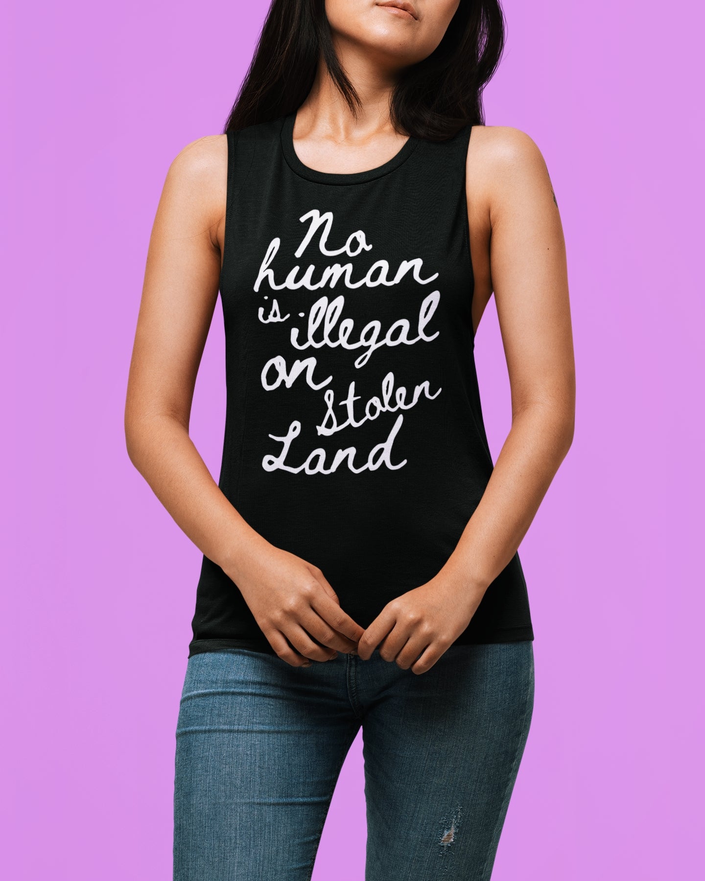 Women's black immigration activism sleeveless shirt with bold cursive that says 'No Human is illegal on stolen land'
